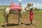 Masai Warrior in traditional red toga pose in front of his camel at Lewa Wildlife Conservancy in North Kenya, Africa