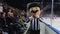 Mascot person in hockey judge suit runs by modern ice arena