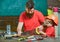 Masculine duties concept. Father, parent with beard teaching little son to sawing with sharp handsaw, carpenter crafts