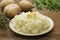 Mashed potatoes with butter and fresh white potatoes on background, wooden table. Healthy food for kids, dinner