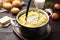 Mashing potatoes in pot on wooden table