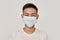 Mask on. Portrait of young asian man wearing medical mask, smiling at camera  over white background. Health care