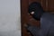 Masked burglar with lock picking tools breaking and entering into house. Crime concept