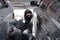 Masked burglar wearing a balaclava ready to burglary against car background. Insurance crime concept.