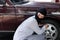 Masked burglar wearing a balaclava ready to burglary against car background. Insurance crime concept