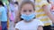 Masked child from an epidemic of coronaviruses or viruses looks at the camera amid masked people from the virus who are