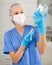 Masked female nurse fills a syringe with saline for injection