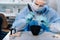 A masked and gloved dental technician works on a prosthetic tooth in his lab