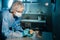 A masked and gloved dental technician works on a prosthetic tooth in his lab