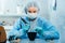 A masked and gloved dental technician works on a prosthetic tooth in his lab