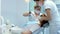 A Masked and Gloved Dentist Explains the Upcoming Treatment to His Female Patient then Starts the Examination, Using