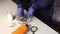 A masked man wearing rubber gloves puts coins in phosphoric acid and checks the cleaning process. Corroded coins and chemicals for