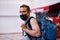 Masked passenger with luggage at the lobby of airport. Tourism during a pandemic of coronavirus. Blurred background.