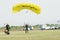 Masked skydiver coming in for landing on grass with open bright