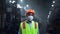 Masked supervisor looking camera at huge energy manufacturing special factory.