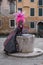 Masked woman in pink and black hand made costume with fan and ornate painted feathered mask at Venice Carnival