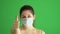Masked woman protects himself from epidemic. Young female wearing medical mask at green screen. Close-up portrait at