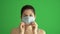 Masked woman protects himself from epidemic. Young female wearing medical mask at green screen. Close-up portrait at