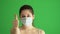 Masked woman protects himself from epidemic. Young female wearing medical mask at green screen. Close-up portrait at