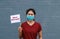 Masked woman and small flag with text New Normal in hand. Concept of living a new way to prevent epidemics and COVID