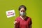 Masked woman and small flag with text New Normal in hand on green background. Concept of living a new way to prevent epidemics and