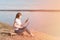 Masked woman working remotely on a laptop outdoors, on the background of the river and sky