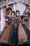 Masked women in costume, with decorated fans, standing in front of the arches at St Marks Square during the Venice Carnival