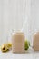 Mason glass jar mugs filled with banana apple smoothie, side view. Close-up