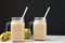 Mason glass jar mugs filled with banana apple smoothie, side view. Closeup