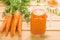 Mason jar with fresh carrot juice on light wooden background