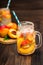 Mason jar glass of homemade peach iced water on a rustic wooden background.