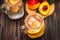 Mason jar glass of homemade peach iced water on a rustic wooden background. Top view.