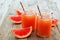 Mason jar glasses of grapefruit juice on rustic wood background