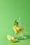 Mason jar with homemade sparkling lemonade with ice, slices of lime and lemon, leaf of mint with plastic straws on a