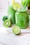 Mason jar mug with fresh vegetable smoothie, bottle with green fruit juice, ingredients apples, citrus, kiwi