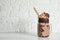 Mason jar of tasty milk shake with sweets on table near brick wall