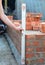 A mason person is using a spirit level to check house brick wall foundation. Brick house wall foundation with bitumen waterproof