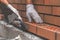 Mason trowels smears cement mortar on brick. Bricklaying when building house or stone fence