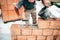 Mason using trowel, pan knife and mortar for brickwork, building outside walls