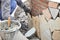 Mason worker installing flagstones on brick wall with mortar