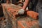 Masonry construction. A mason person, a bricklayer is laying, installing bricks, using a mortar and a trowel, building a brick