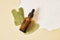 massage oil in dropper bottle and jadeite gua sha scrapers, background of beige torn paper and texture