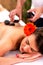 Masseur placing heated stones on the back of his client