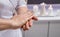 Masseur putting aroma oil on her hands, preparing for massage in spa center