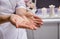 Masseur putting aroma oil on her hands, preparing for massage in spa center