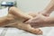 A masseuse applying lymphatic drainage to the soles of a patient\'s feet