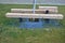 Massive bench in the park under a tree in the park urban style beam shape on metal legs in the square. grass grate made of metal a