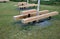 Massive bench in the park under a tree in the park urban style beam shape on metal legs in the square. grass grate made of metal a