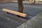 Massive bench in the park under a tree in the park urban style beam shape on metal legs in the square. grass grate made of metal a