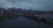 Massive bridge over Charles river and cityscape at dusk on cloudy day. Backwards descending fly above water surface